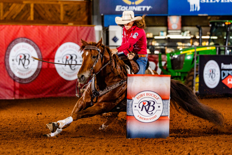 Brittany Tonozzi turns a barrel on a red horse in a red shirt