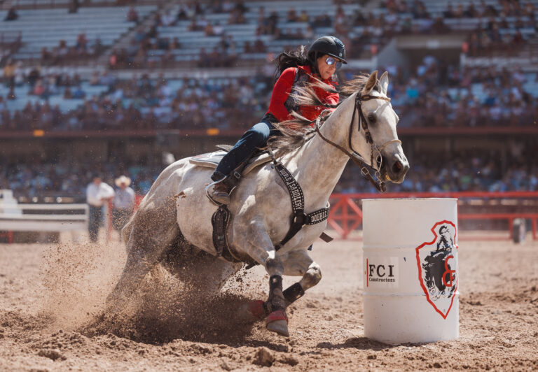 Anita Ellis turns a barrel on her white horse at Cheyenne Frontier Days