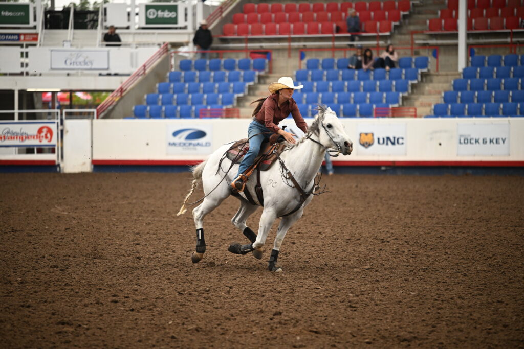 Emma Smith turns a barrel on a grey horse
