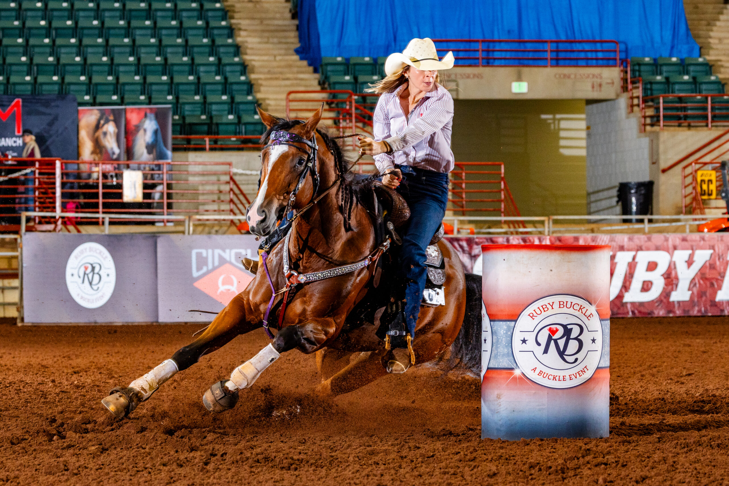 A girl in a cowboy hat turns a barrel on a quarter horse