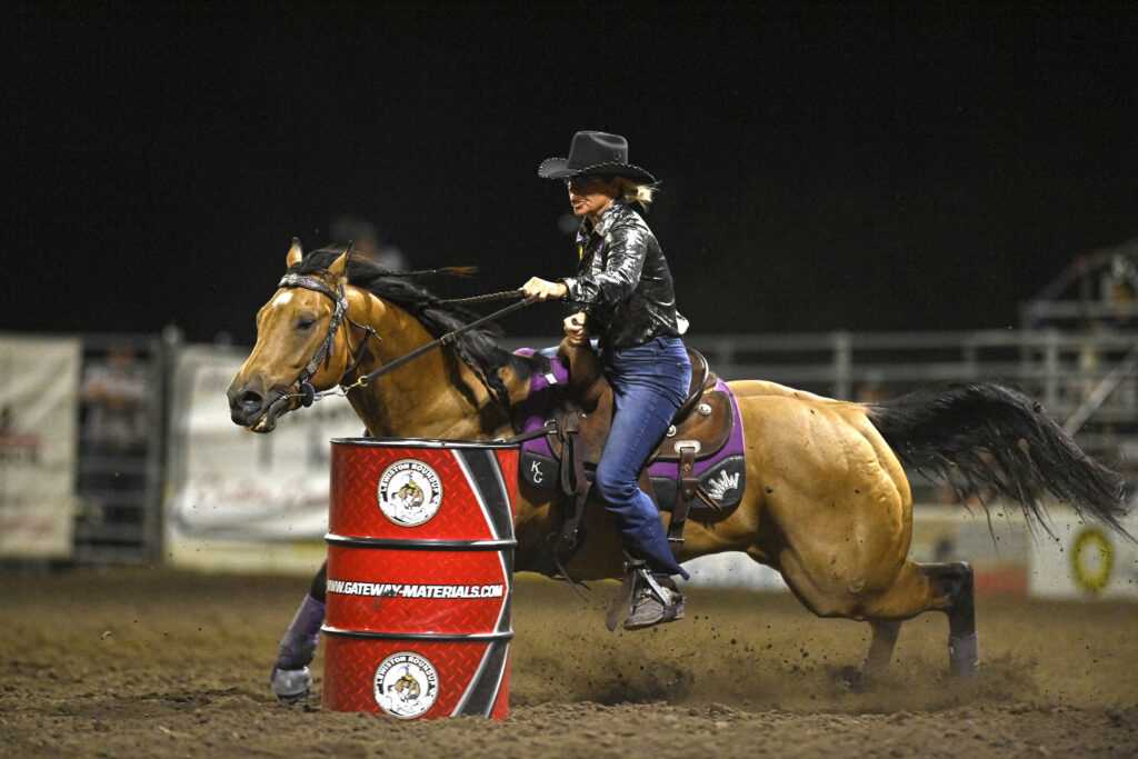 Kathy Grimes turns a barrel on her buckskin horse