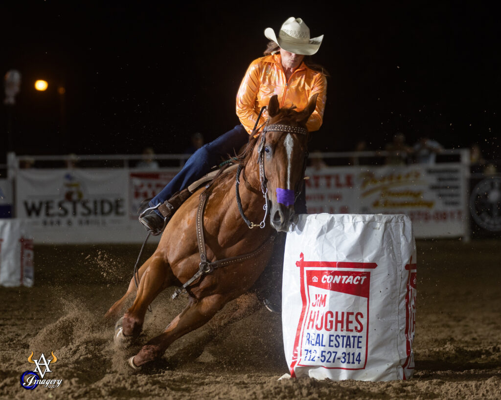 Lucy Ferch turns a barrel in an orange shirt on a red horse