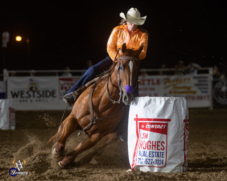 Lucy Ferch turns a barrel in an orange shirt on a red horse
