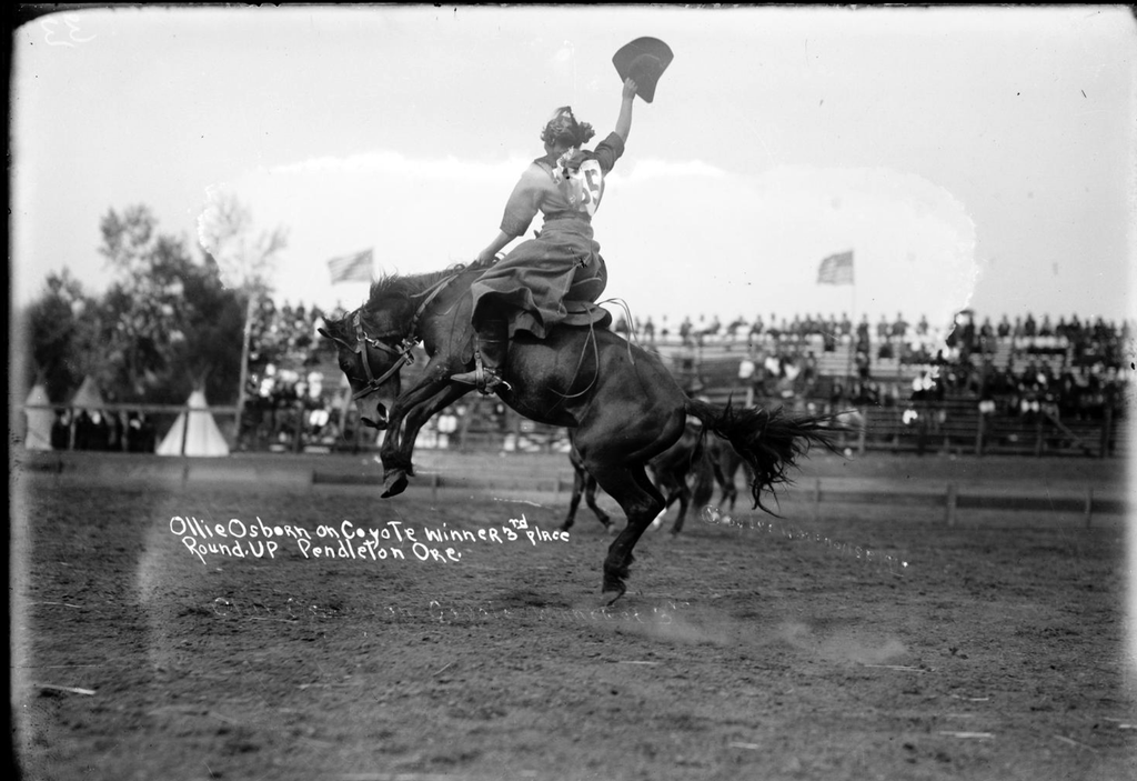 woman on bronc waving hat at pendleton