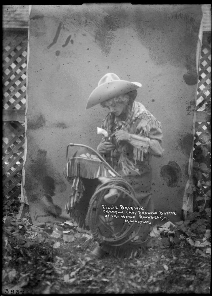 A woman in classic cowgirl attire poses for a portrait 