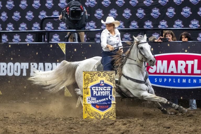 Makenzie Mayes turns a barrel on her white horse