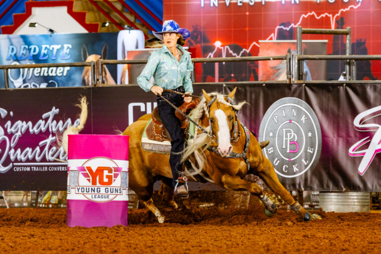 Tricia Aldridge turns a barrel in a purple hat on her yellow horse