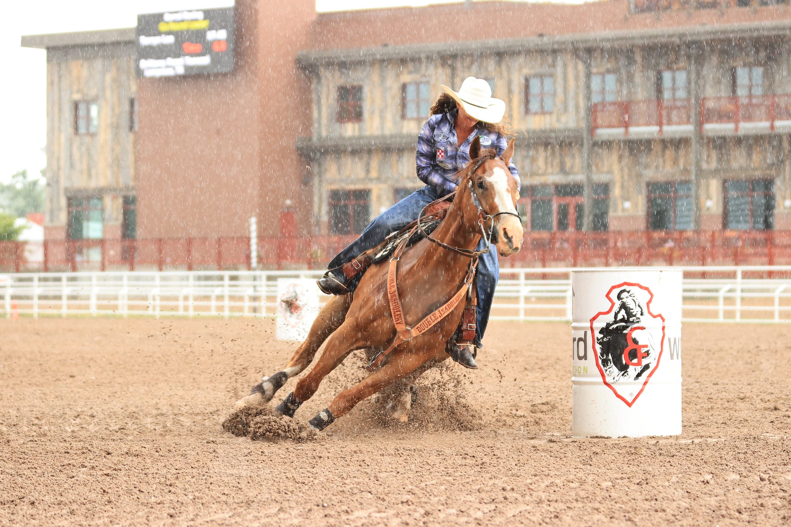 A woman turns a barrel on a red horse in the rain 