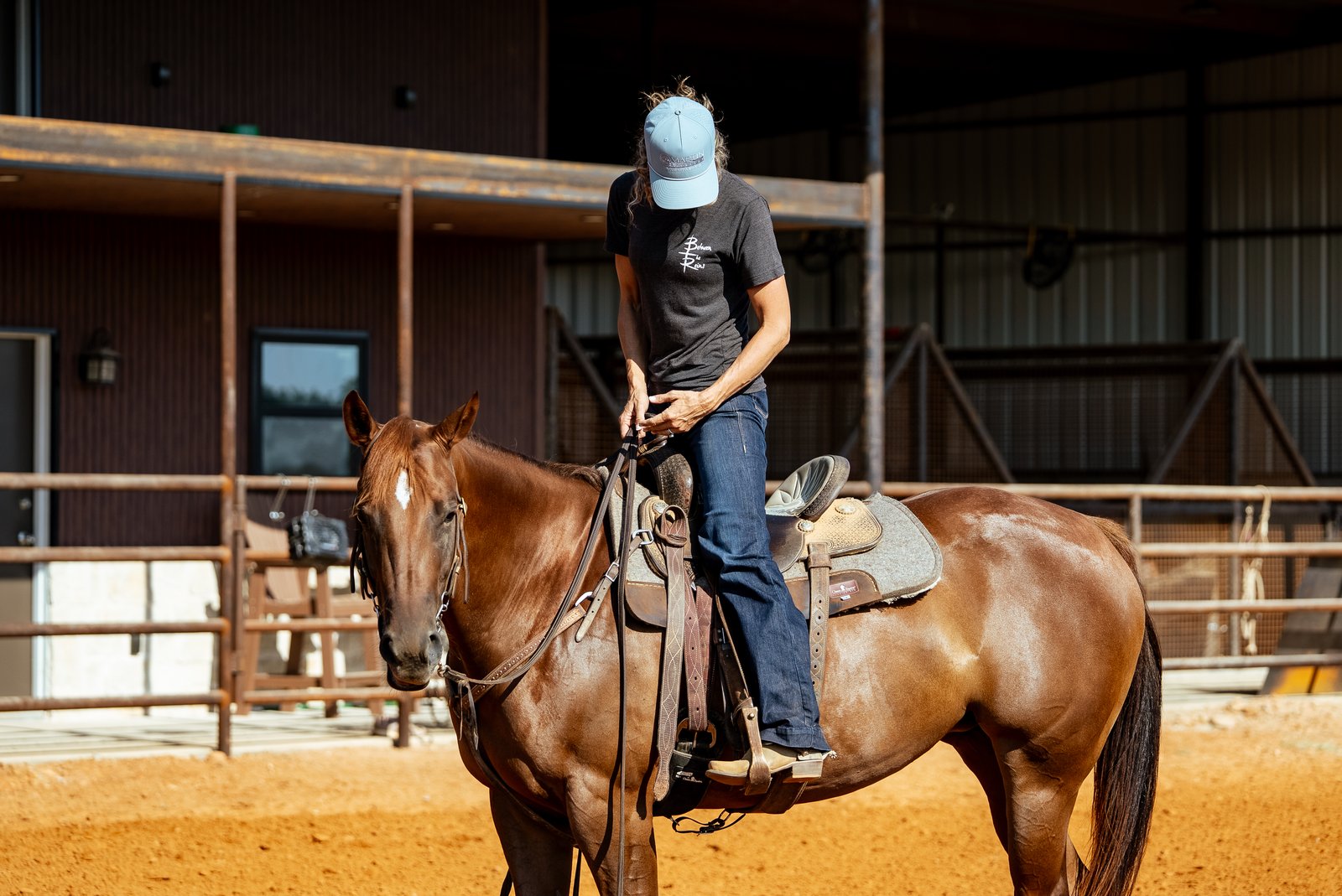 Ashley Schafer sitting on a sorrel horse in a covered arena