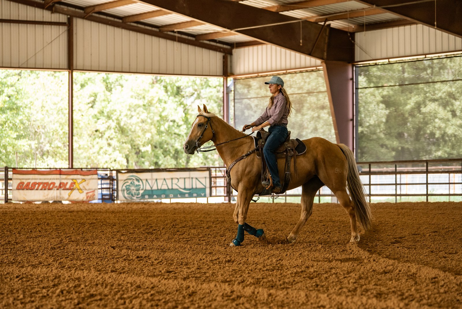 Kimmi Byler riding a palomino horse in a covered arena
