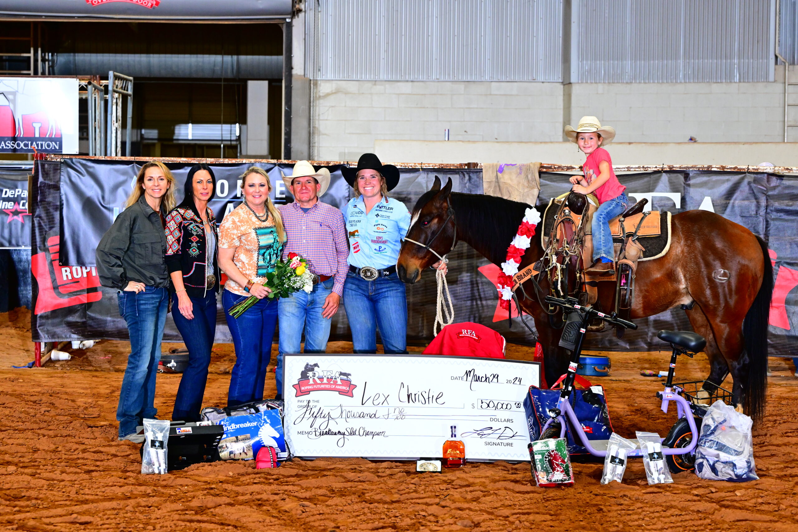 Taylor Munsell stands alongside Lex Christie and his family after winning a total of $73,000 at the RFA Waco Breakaway Slot Roping.