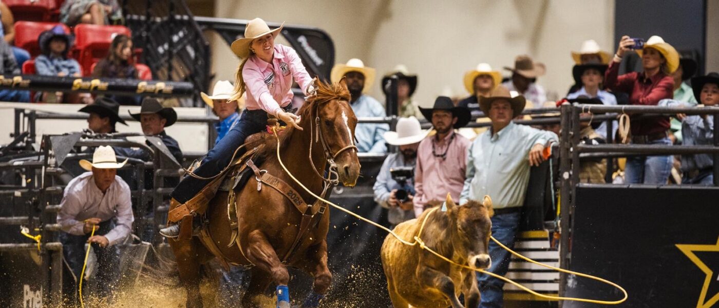 Hadley Thompson ropes a calf in a pink shirt