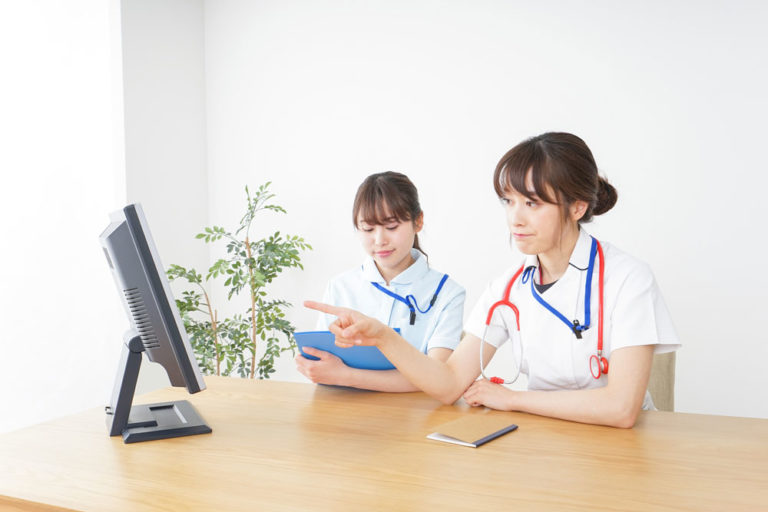 computer two Asian doctors one pointing at screen