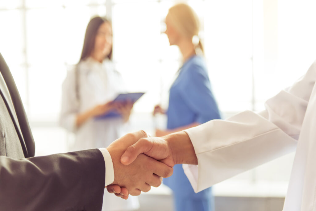 Handshake between business people, representing corporatization of equine practice