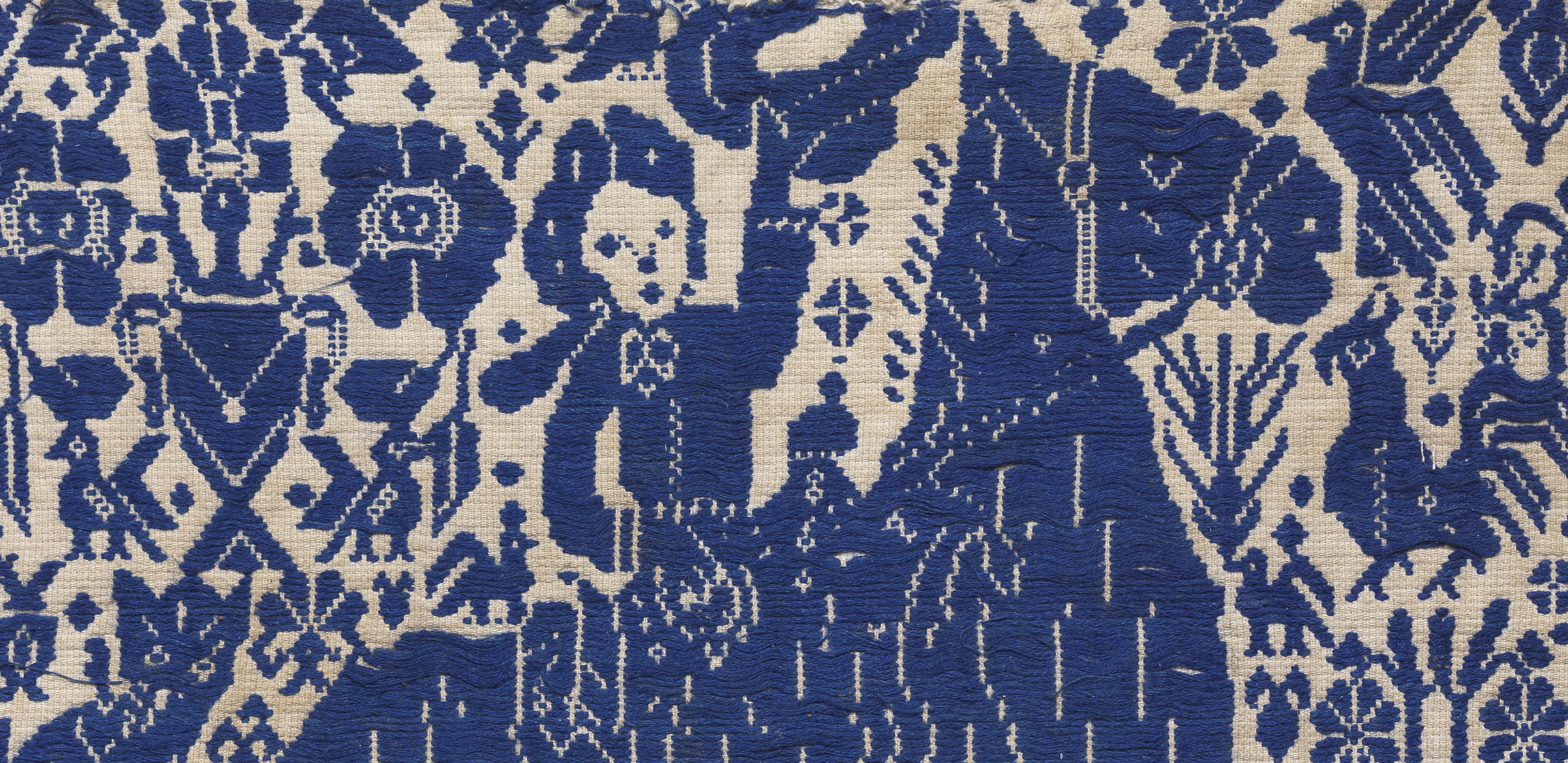 Closeup of equestrian figure on horseback woven into a blue and white textile