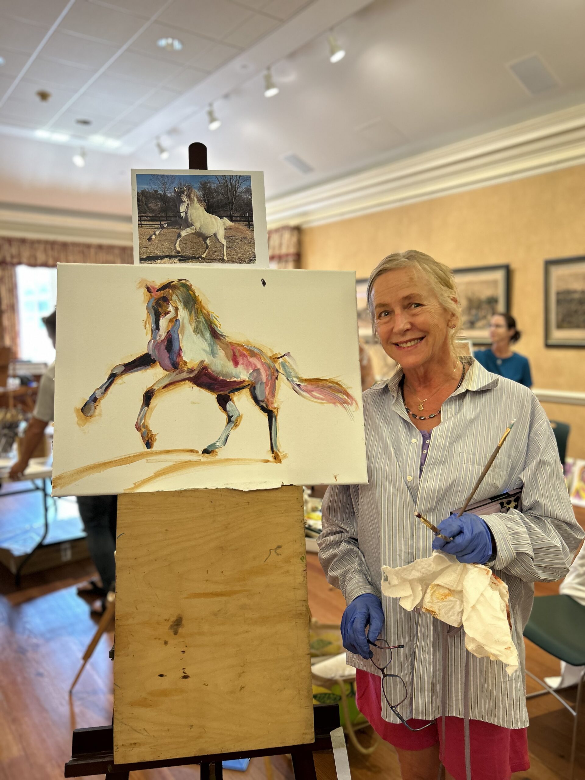 Female artist poses with painting of a horse