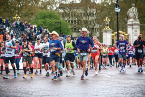 two men wearing cowboy hats run in a crowd of marathon runners