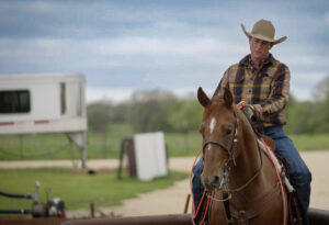 Team roper Tate Kirchenschlager sits horseback in a roping box, holding a rope