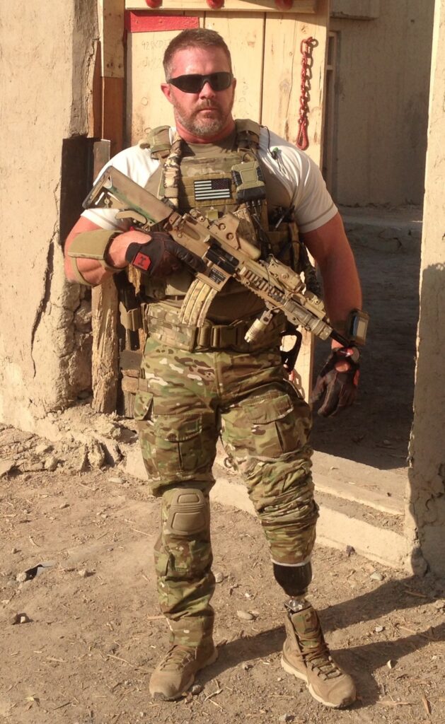 Retired Army Capt. Chad Fleming in tactical gear on deployment, with a prosthetic leg visible