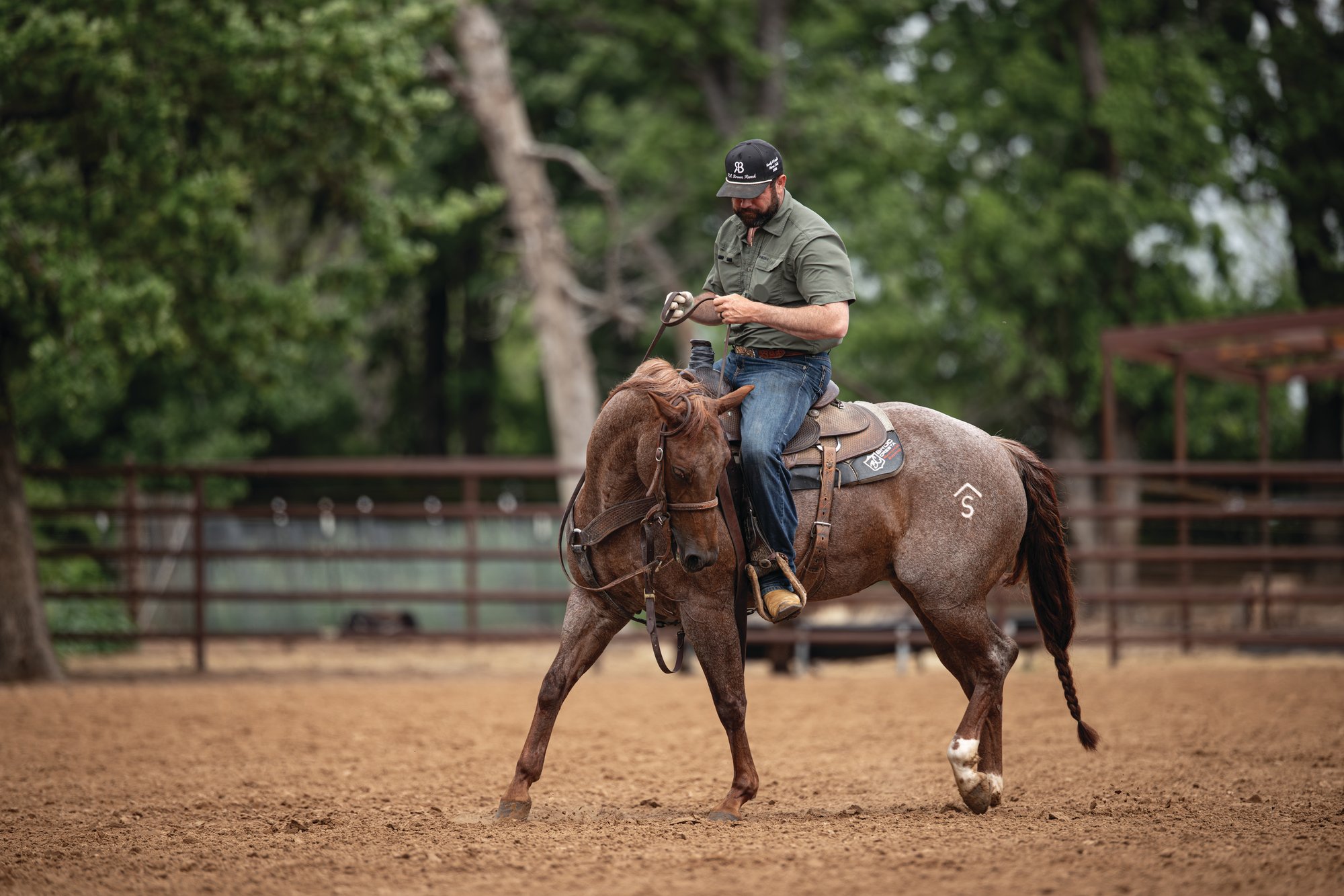 Paul Eaves riding a red roan horse in a practice pen