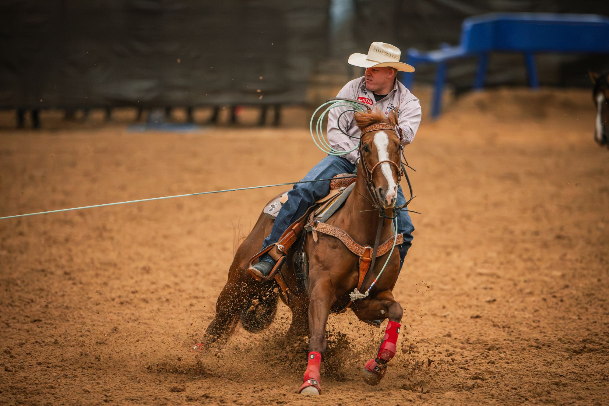 A header in a straw hat turns a sorrel horse with a white blaze and red leg boots in the Amarillo arena.