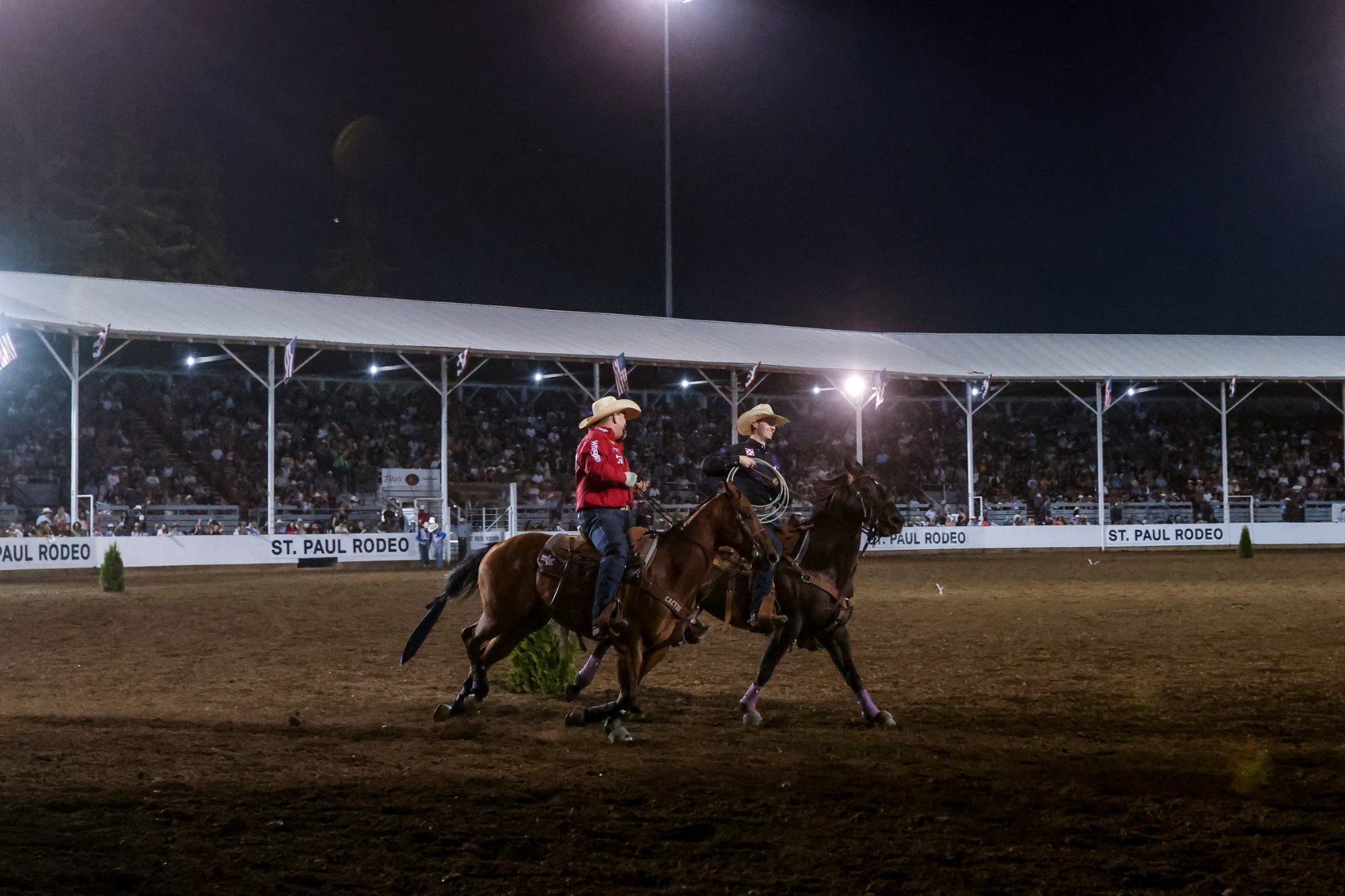 Brenten Hall and Wyatt Cox take a victory lap on horseback in front of the St. Paul Rodeo grandstand.