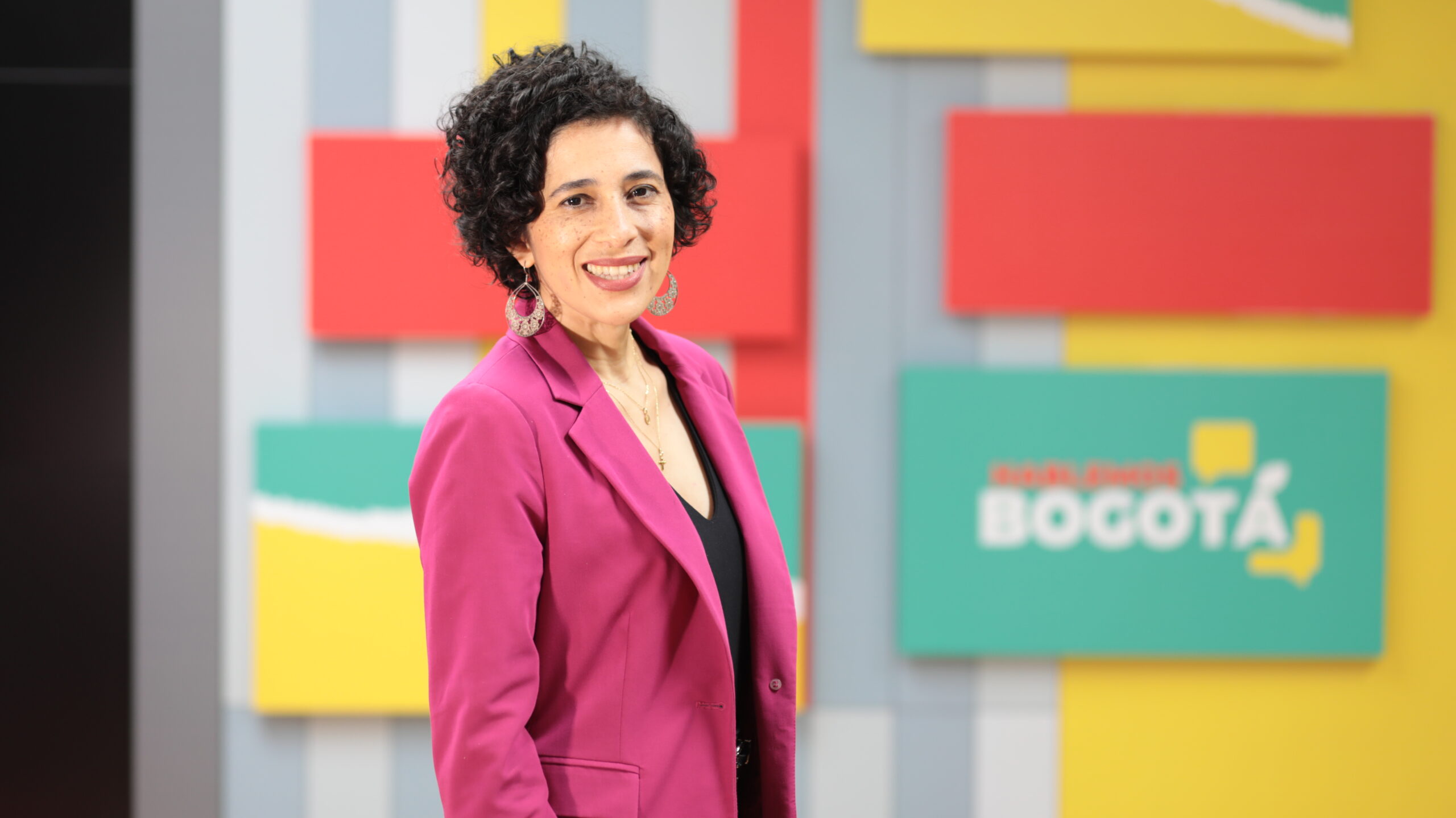 Magda Páez Torres, periodista de Hablemos Bogotá. Vestida con un saco rosado, en el set de Hablemos Bogotá.