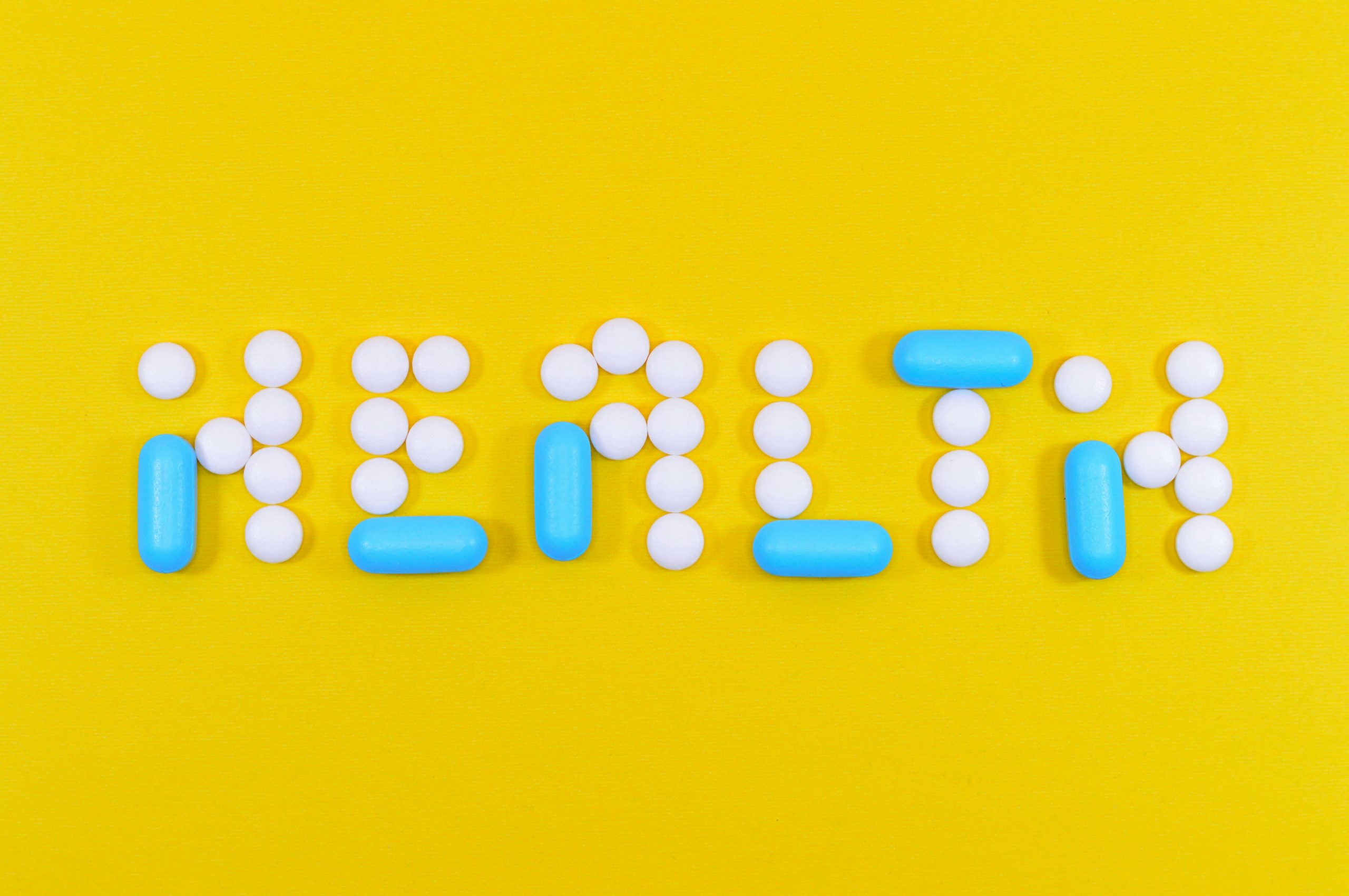 White and blue health pill and tablet letter cutout on yellow surface
