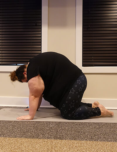 plus size woman doing yoga cat pose