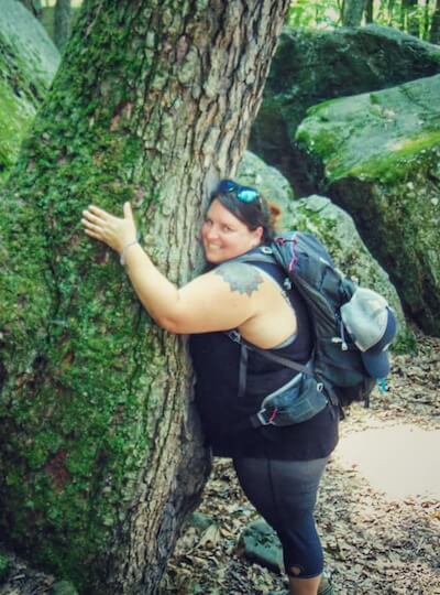 Andrea DiMaio on a hike, hugging a tree.