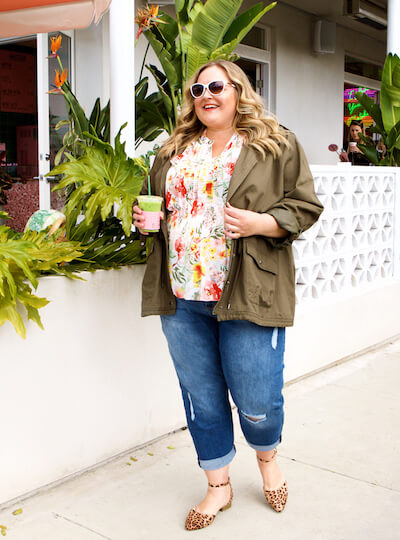 Reah Norman in boyfriend jeans, floral top, and cargo jacket.