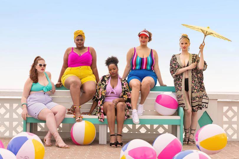 Plus size models wearing swimwear and cover ups at the beach