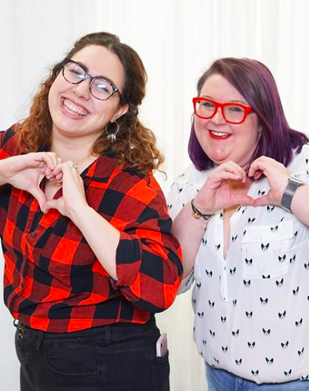 dia community woman in buffalo plaid shirt woman with red glasses making heart signs with their hands