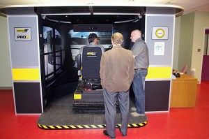 Minister Virk gets instruction from head instructor Darren Hood while COTR President and CEO David Walls watches.
