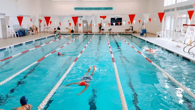 People swimming in lanes in an indoor pool.
