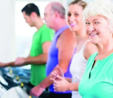An elderly lady with three adults using the treadmill.