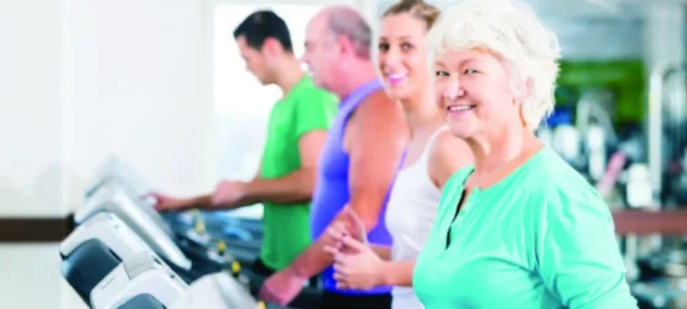 An elderly lady with three adults using the treadmill.