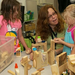 An instructor or mentor with four children playing with wooden blocks.
