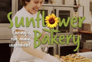 A smiling baker wearing gloves arranges pastries on a tray in an industrial kitchen. Text on image reads "Sunflower Bakery: Caring is our main ingredient.