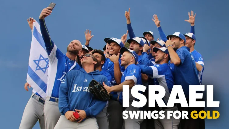 A group of baseball players in Israel uniforms take a selfie together, holding an Israeli flag; text reads "Israel Swings for Gold.