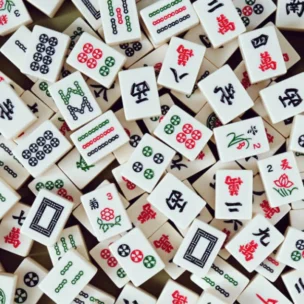 A large pile of Mahjong tiles featuring various Chinese characters, numbers, and symbols in green, red, and black.
