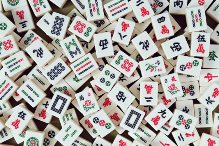 A large pile of Mahjong tiles featuring various Chinese characters, numbers, and symbols in green, red, and black.