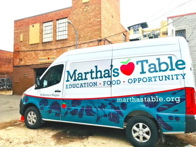 A Martha's Table delivery van is parked outside a brick building, displaying the organization's name, website, and the words "Education • Food • Opportunity.