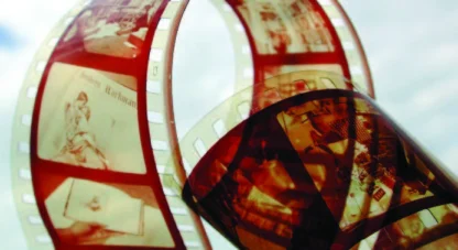 A close-up of two strips of photographic film negatives showing various images, with a blurred background.