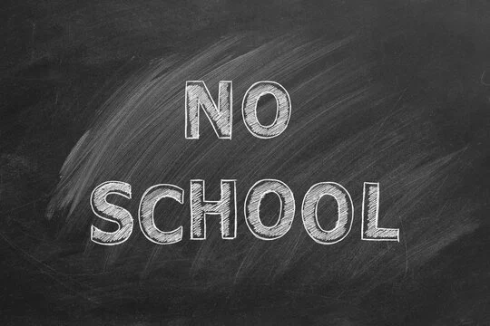 A chalkboard with the words “NO SCHOOL” written in large, white chalk letters.