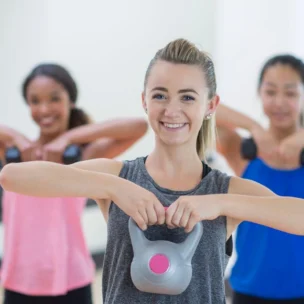 Three women exercising with kettlebells in a gym.