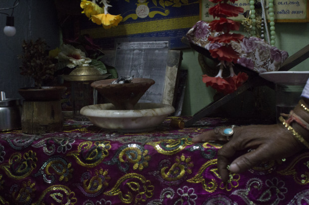 Here, Rumanaben lights incense, pours water for the saint, and reads. Photo by Darcy Coulter.