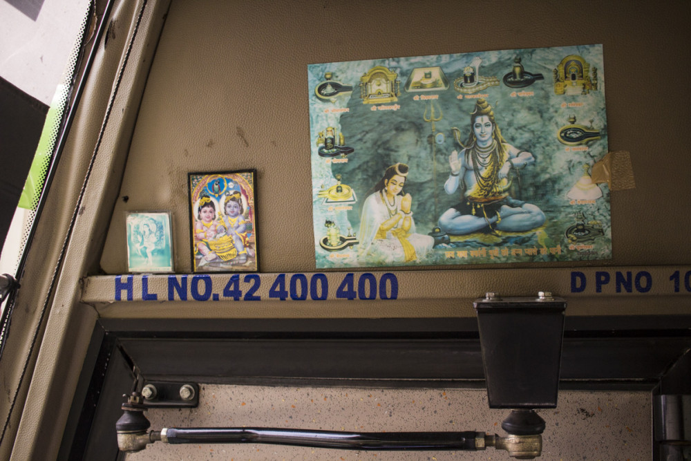 Pictures of deities hangs overhead on a bus.