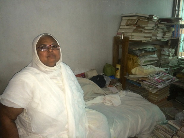 Sadhvi Balaji sits on her bed surrounded by stacks of Jain literature and Scriptures. Study is fundamental to Balaji's religious practice. Photo by Arielle Dreher.