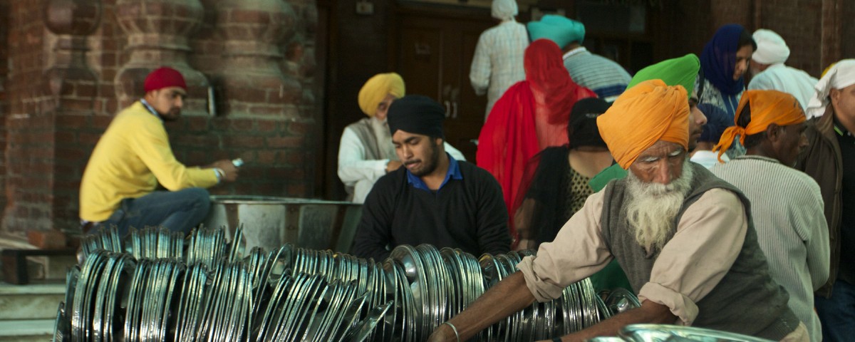 A volunteer at Amritsar’s Golden Temple stacks metal plates. Over 300,000 plates, spoons and bowls are used at the langar here. Photo by Jenna Belhumeur.